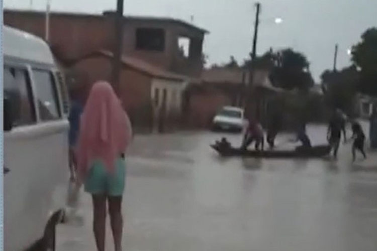 Moradores usam canoa para atravessar alagamento após forte chuva no oeste da Bahia