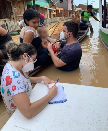 Dentro da água, médico atende bebê em cidade inundada por rio no Acre