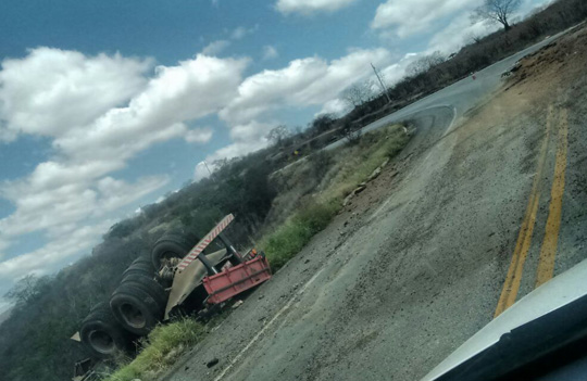 Carreta bitrem carregada de pedras de mármore capota e danifica asfalto na BA-262